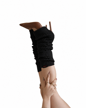 A person's leg and foot wearing a black ribbed knit boot cover over a brown pointed-toe stiletto heel, shown against a solid white background.